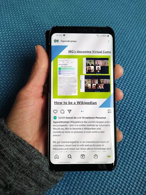 Hand holding a smartphone showing a social media post
